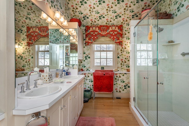 full bathroom featuring a sink, a shower stall, and wallpapered walls