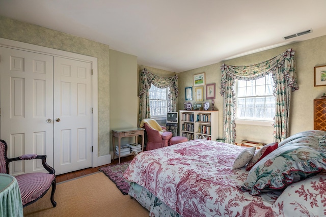 bedroom featuring wood finished floors, visible vents, and a closet