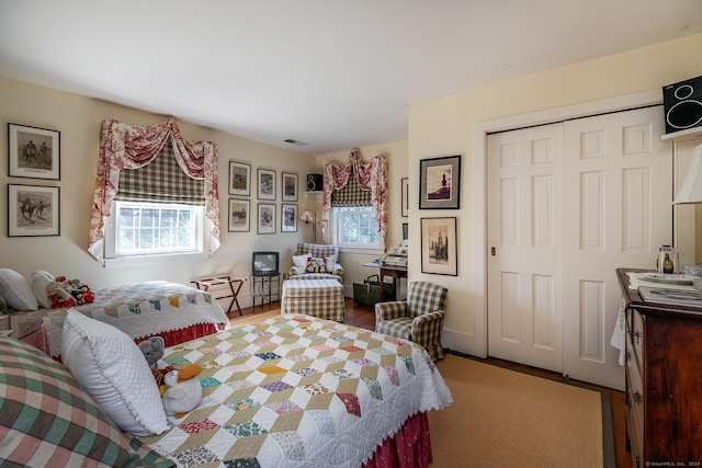 bedroom featuring a closet, baseboards, visible vents, and wood finished floors