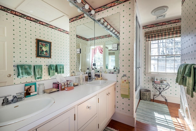 full bathroom with wallpapered walls, wood finished floors, and a sink