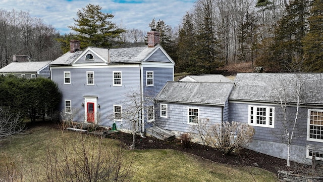 back of property featuring a chimney and a yard