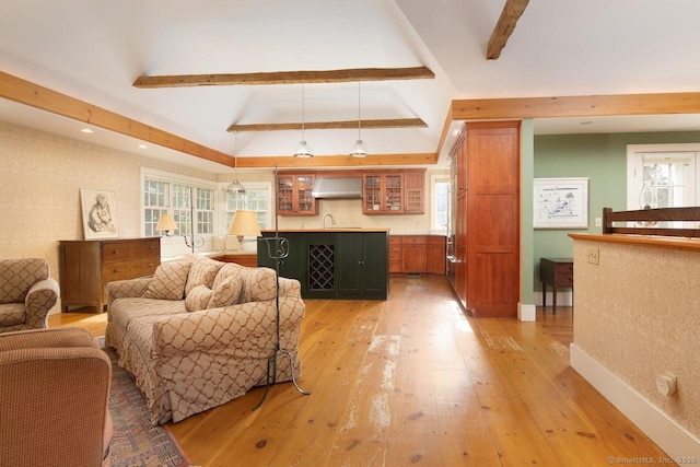 living room featuring plenty of natural light, vaulted ceiling with beams, and light hardwood / wood-style floors