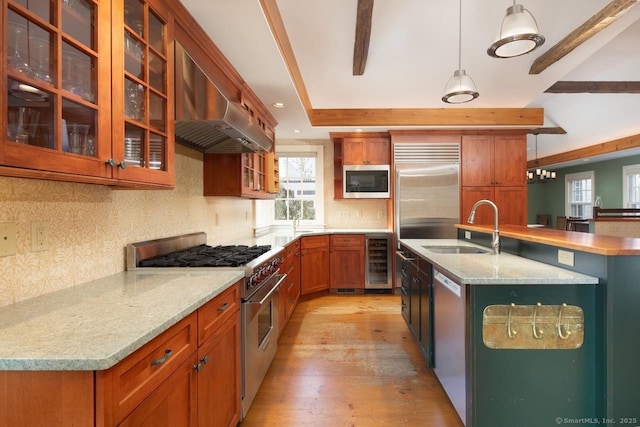 kitchen with wine cooler, sink, built in appliances, ventilation hood, and decorative light fixtures