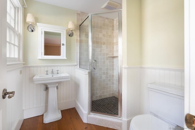 bathroom with hardwood / wood-style flooring, a shower with shower door, and toilet