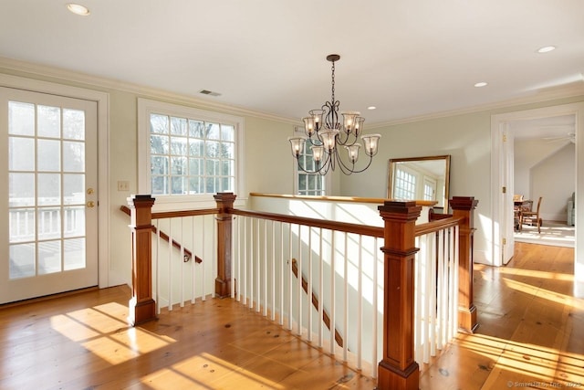 staircase featuring hardwood / wood-style flooring, ornamental molding, and a chandelier