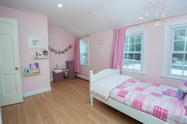 bedroom featuring baseboard heating, multiple windows, and light hardwood / wood-style flooring