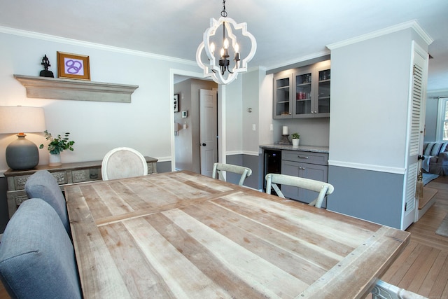 dining space featuring hardwood / wood-style floors, ornamental molding, beverage cooler, and a chandelier