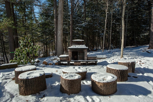 snow covered patio with an outdoor stone fireplace