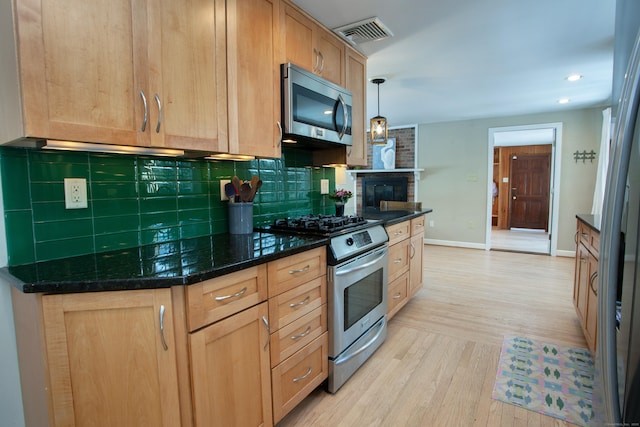 kitchen featuring pendant lighting, backsplash, dark stone counters, light hardwood / wood-style floors, and stainless steel appliances