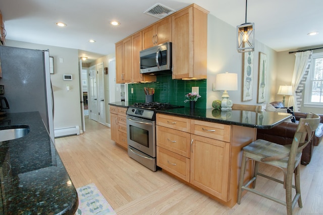 kitchen with pendant lighting, tasteful backsplash, a baseboard radiator, stainless steel appliances, and light hardwood / wood-style flooring