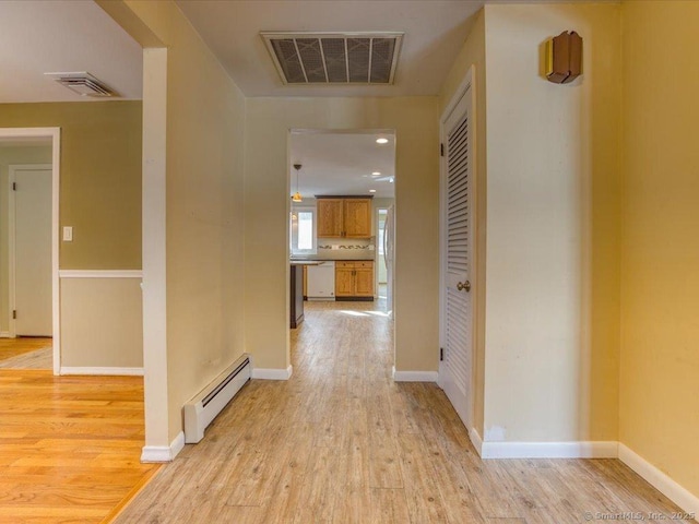 corridor with light hardwood / wood-style floors and baseboard heating