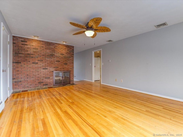 unfurnished living room featuring light hardwood / wood-style flooring, a fireplace, ceiling fan, and brick wall