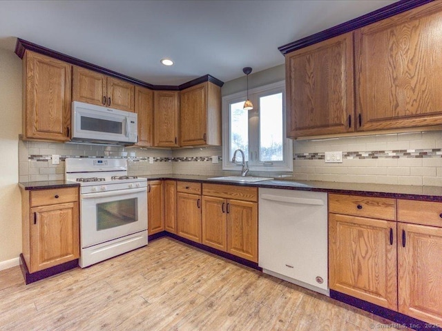 kitchen with sink, white appliances, light hardwood / wood-style floors, and hanging light fixtures