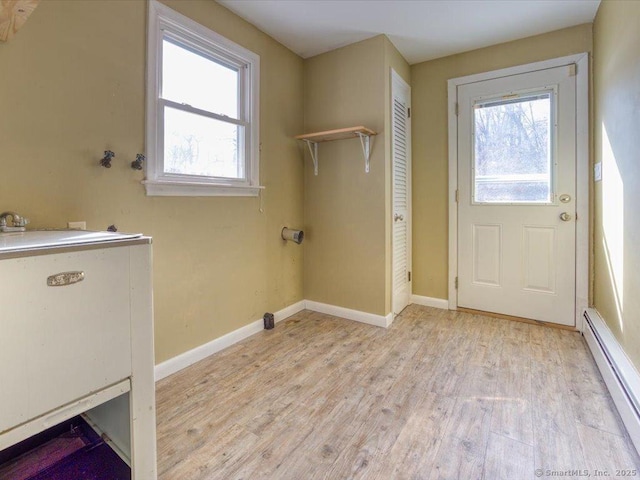 washroom with light hardwood / wood-style flooring, a baseboard heating unit, and plenty of natural light