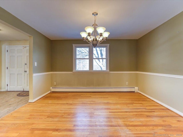 unfurnished room with an inviting chandelier, a baseboard heating unit, and light hardwood / wood-style flooring