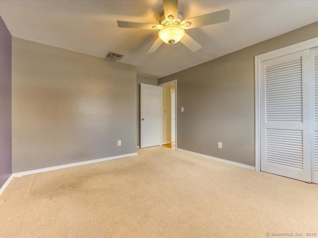 unfurnished bedroom featuring light colored carpet, a closet, and ceiling fan