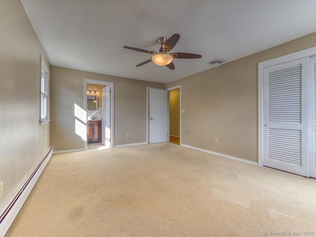 unfurnished bedroom with connected bathroom, a baseboard heating unit, light carpet, and ceiling fan