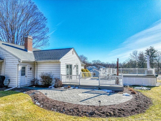 back of house featuring a wooden deck and a lawn