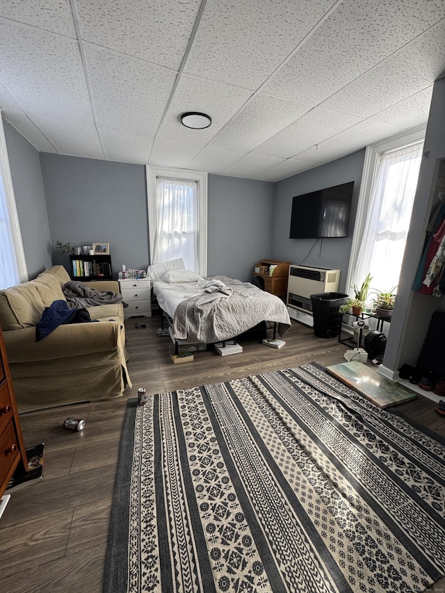 bedroom with a paneled ceiling, wood-type flooring, and multiple windows