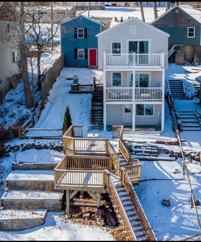 snow covered rear of property with a balcony