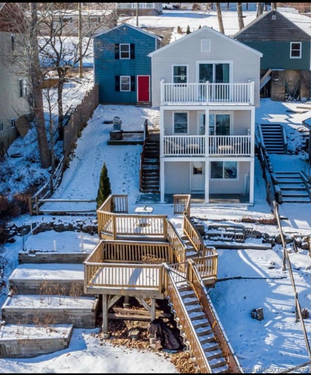 snow covered rear of property with a balcony