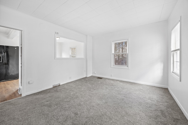 carpeted spare room with crown molding and a healthy amount of sunlight