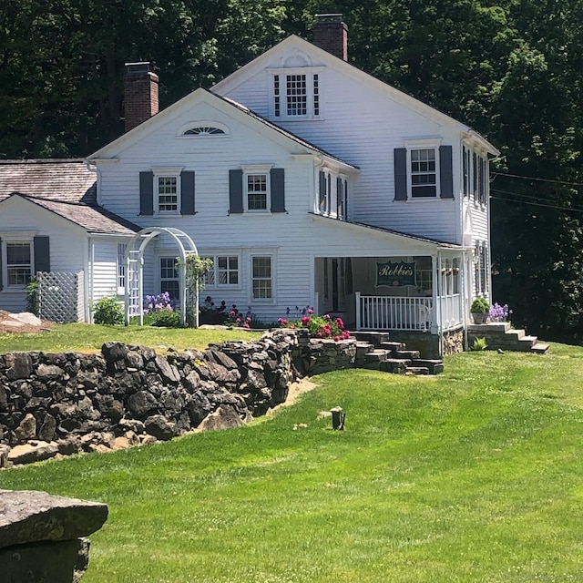 rear view of house featuring a lawn and a porch