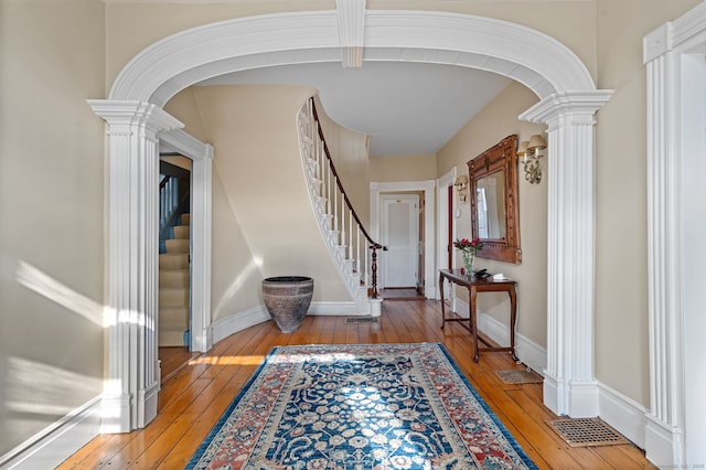 foyer entrance featuring light wood-type flooring and ornate columns