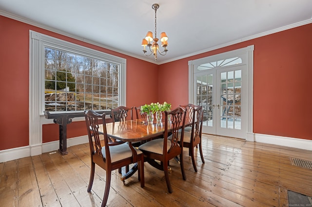 dining room with crown molding, wood-type flooring, french doors, and a notable chandelier