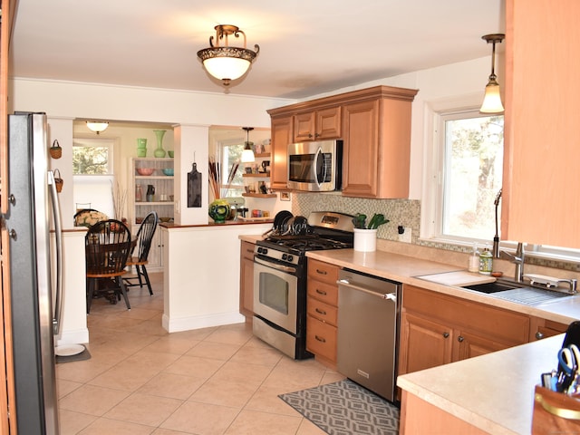 kitchen featuring sink, decorative light fixtures, light tile patterned floors, stainless steel appliances, and backsplash