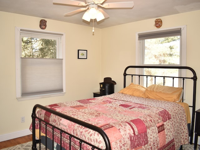 bedroom with multiple windows, hardwood / wood-style floors, and ceiling fan