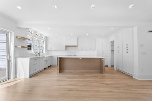 kitchen featuring white cabinetry, a center island, sink, and light hardwood / wood-style floors