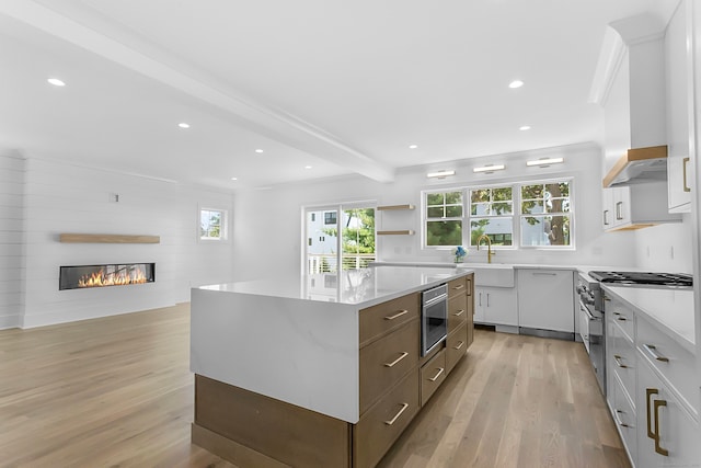 kitchen featuring appliances with stainless steel finishes, white cabinetry, sink, a center island, and light hardwood / wood-style floors