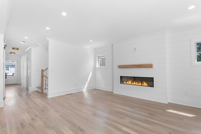 unfurnished living room with a healthy amount of sunlight, a large fireplace, and light wood-type flooring