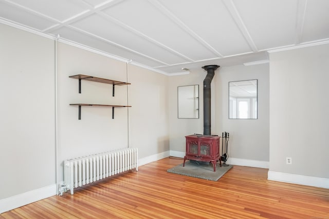 interior space featuring radiator, ornamental molding, hardwood / wood-style floors, and a wood stove