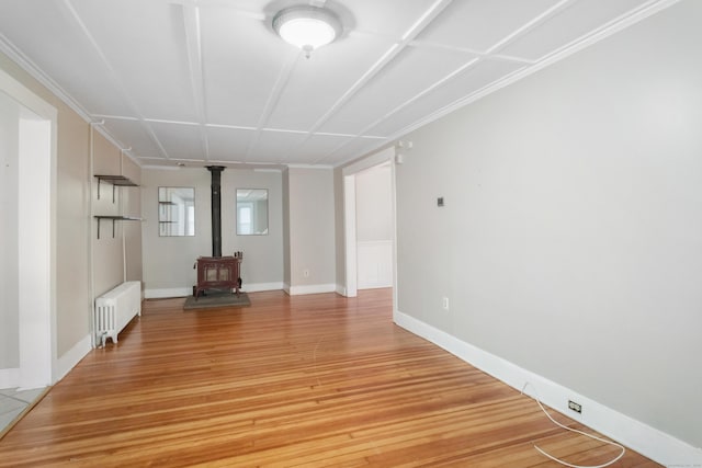 unfurnished living room with radiator, a wood stove, and light wood-type flooring