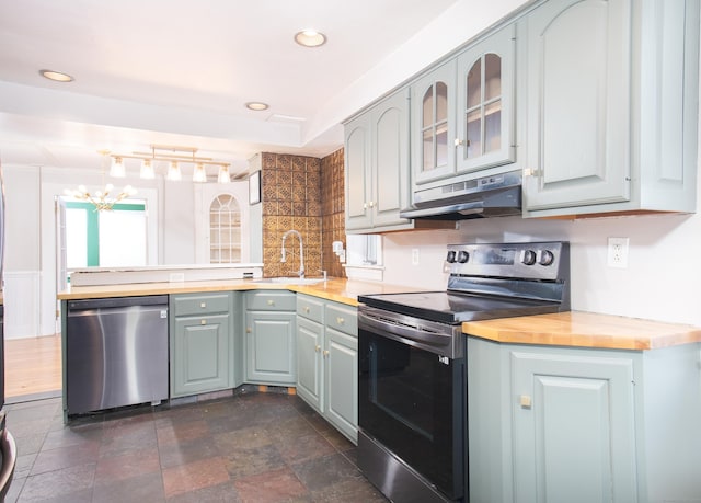 kitchen with appliances with stainless steel finishes, wood counters, sink, gray cabinetry, and kitchen peninsula