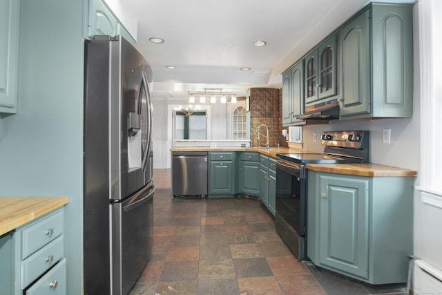 kitchen with sink, butcher block countertops, a baseboard radiator, kitchen peninsula, and stainless steel appliances