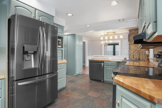 kitchen with sink, green cabinets, butcher block counters, stainless steel appliances, and kitchen peninsula