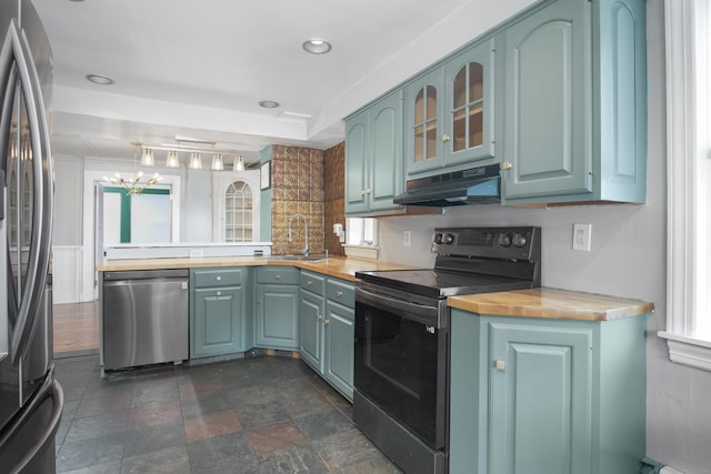 kitchen featuring stainless steel appliances, sink, butcher block countertops, and a notable chandelier