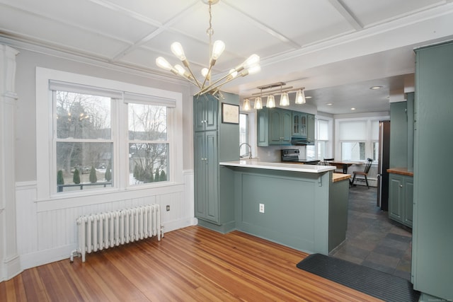 kitchen featuring hardwood / wood-style flooring, radiator heating unit, a notable chandelier, stainless steel electric range oven, and kitchen peninsula