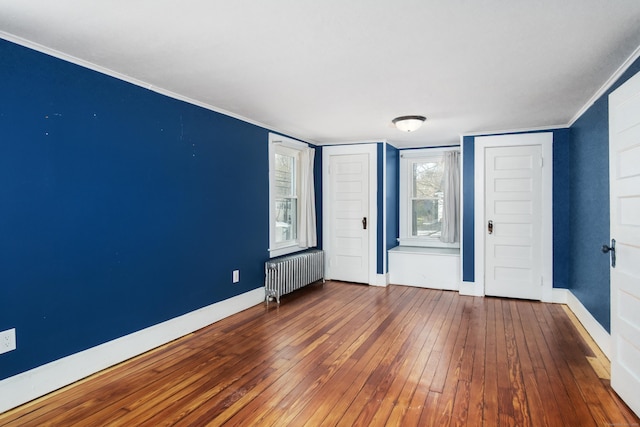 empty room featuring crown molding, radiator heating unit, and hardwood / wood-style floors