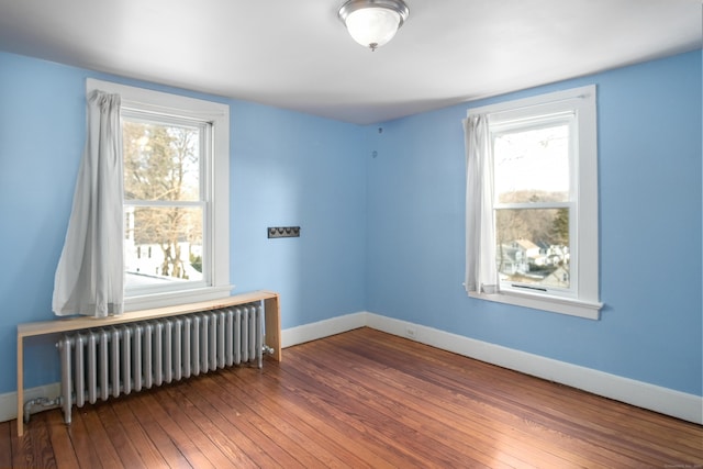 spare room with radiator heating unit and hardwood / wood-style floors