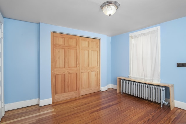 unfurnished bedroom with radiator, dark wood-type flooring, and a closet