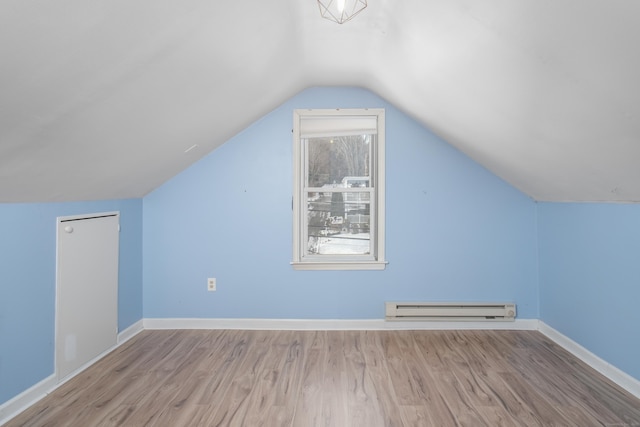 additional living space featuring a baseboard heating unit, light hardwood / wood-style flooring, and vaulted ceiling