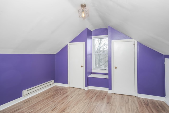 additional living space featuring baseboard heating, vaulted ceiling, and light hardwood / wood-style floors