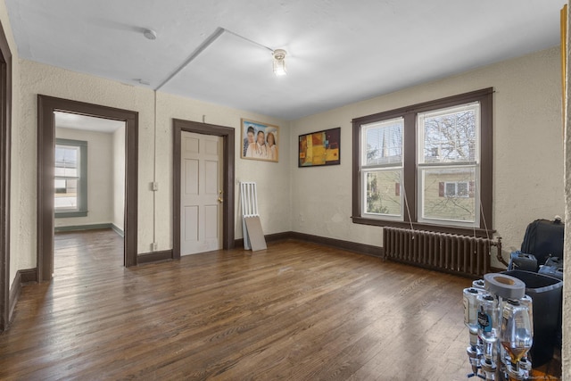 empty room featuring radiator heating unit and dark hardwood / wood-style flooring