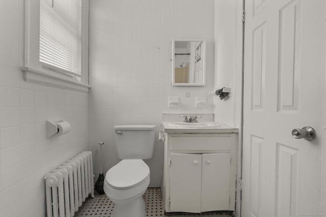 bathroom with vanity, radiator heating unit, tile walls, and toilet