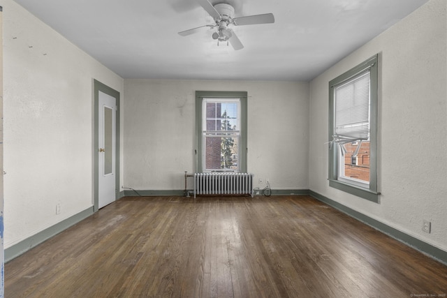 unfurnished room featuring dark hardwood / wood-style flooring, radiator, and ceiling fan