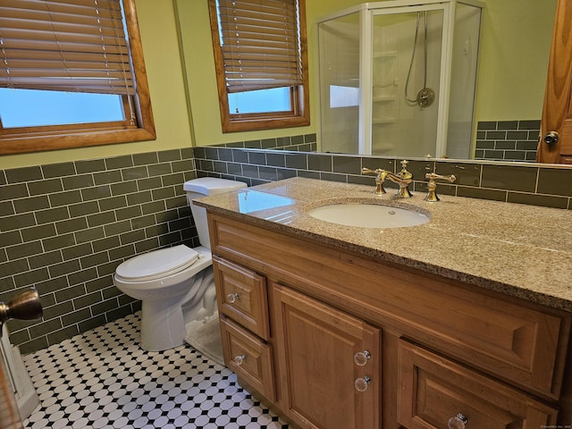 bathroom featuring vanity, a shower with shower door, tile walls, and plenty of natural light